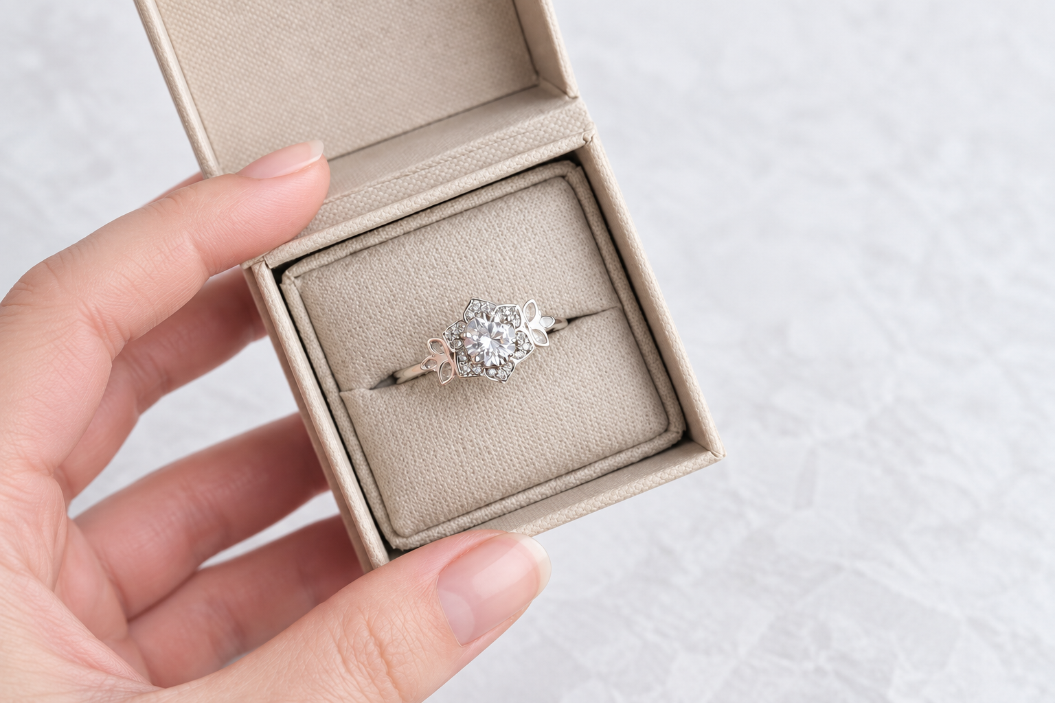 A silver ring with butterfly details in an open linen jewellery box